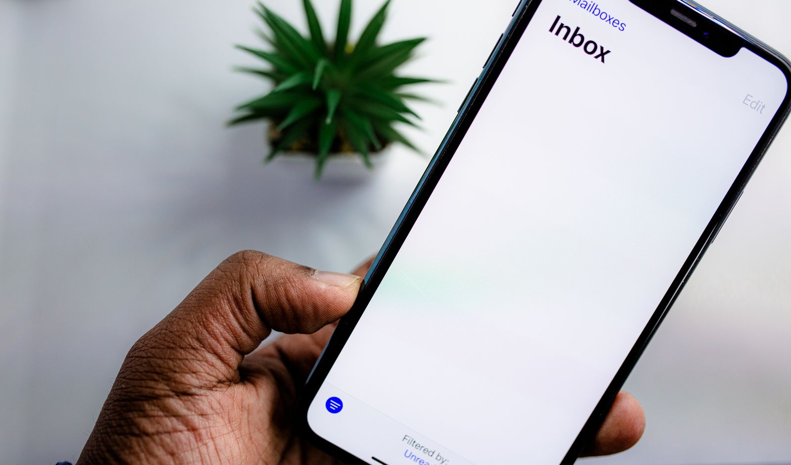 A hand holding a phone showing an empty email inbox