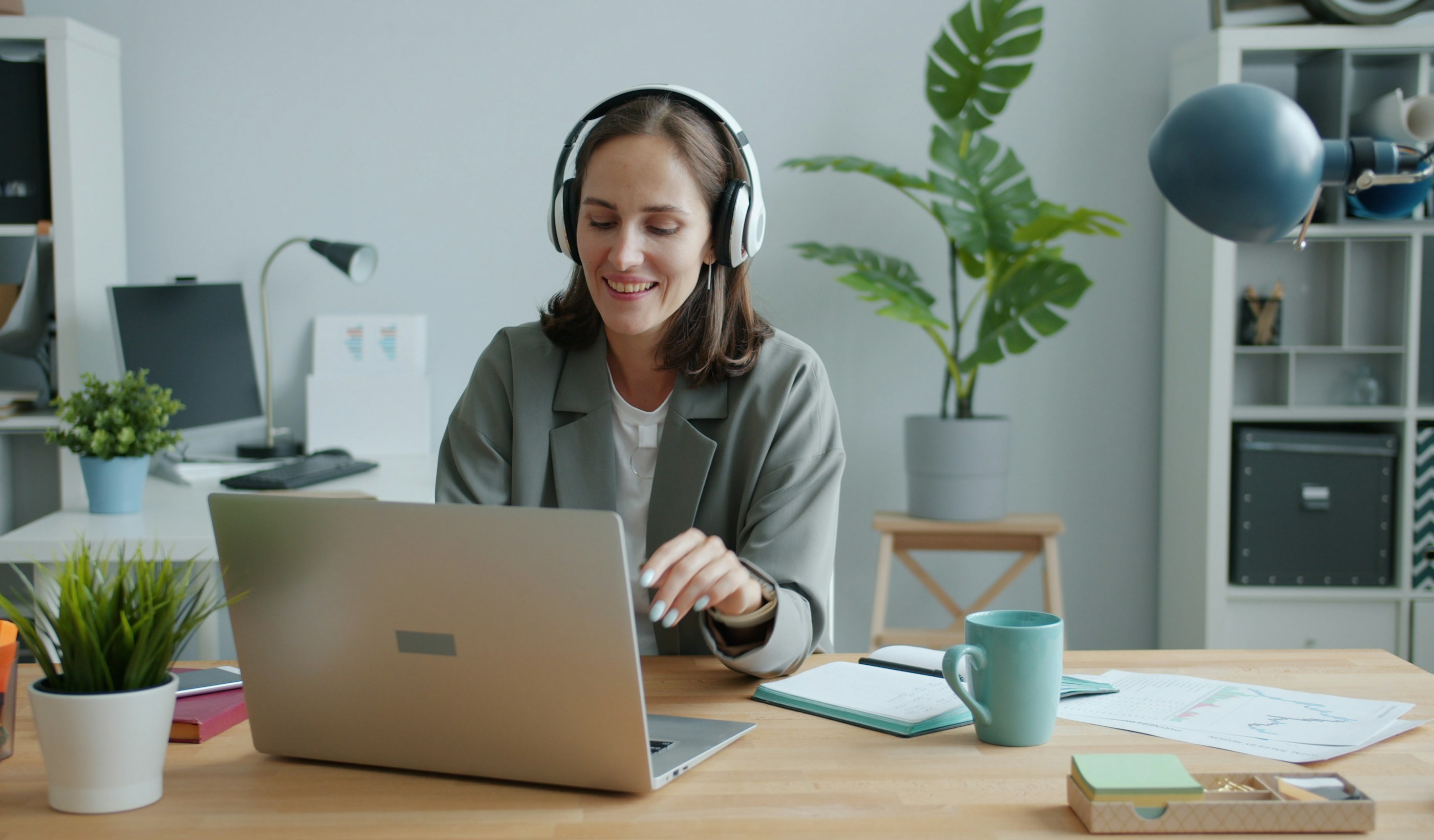A person wearing headphones working at a laptop at a desk