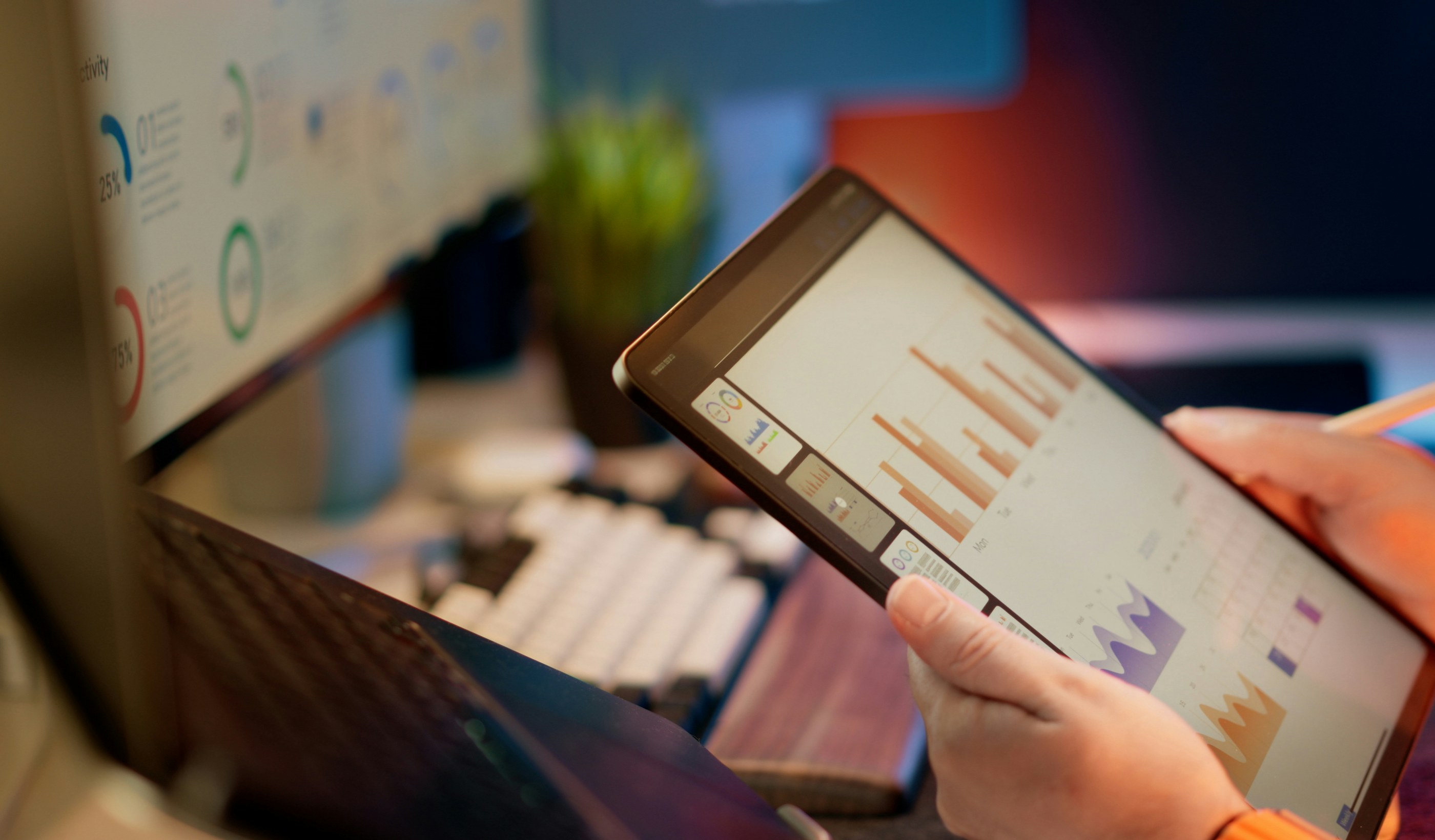 A person reviewing financial data on a tablet held above a desk