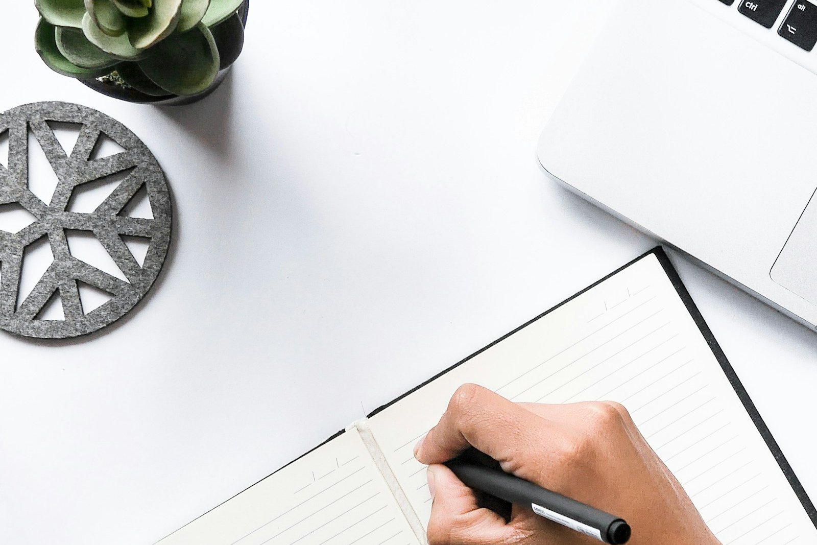 A person writing by hand in a blank notebook