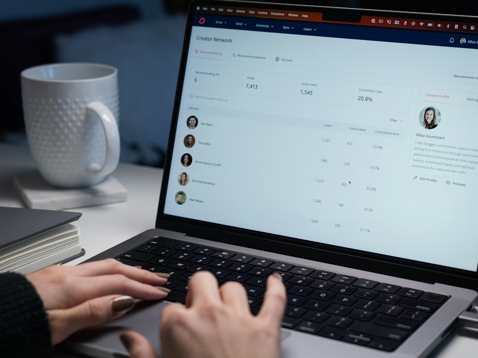 Hands typing on a laptop next to a mug