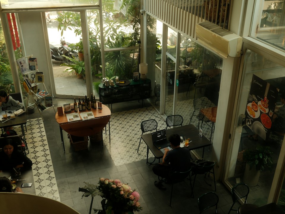 The interior of a cafe with plants and tables, seen from above
