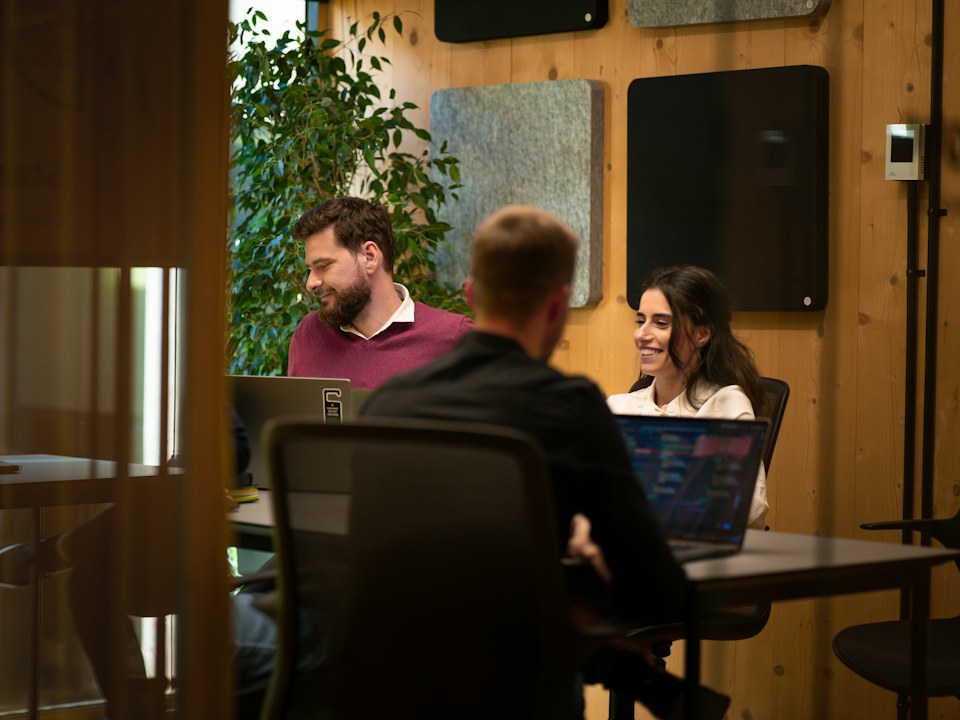 A team sitting around a table with laptops in a meeting