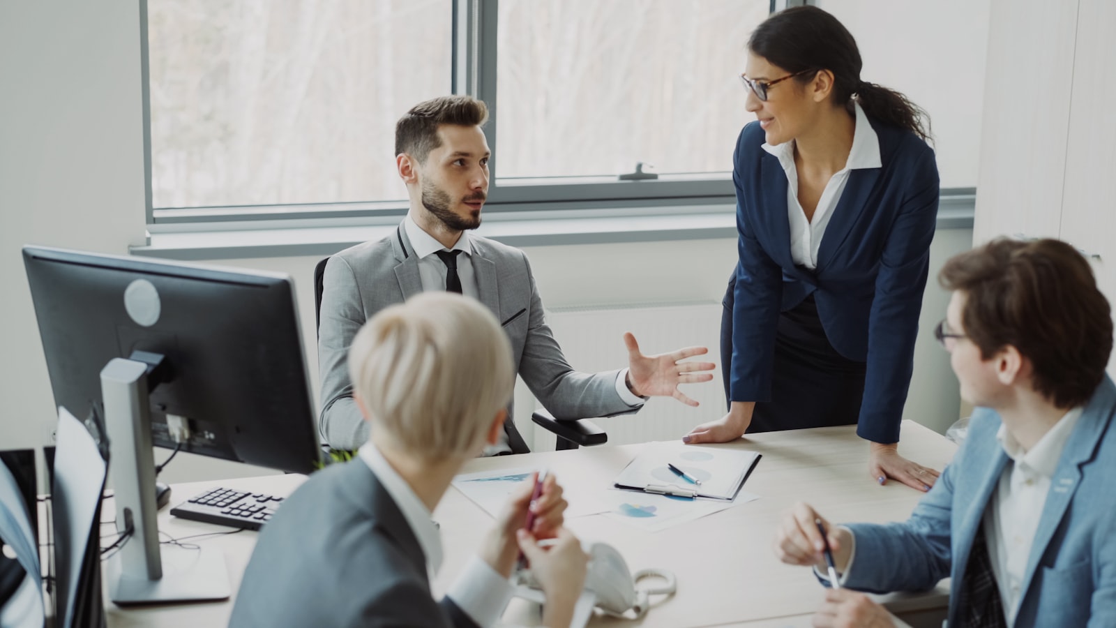 A young businessman talking with colleagues sitting at a table in a modern office
