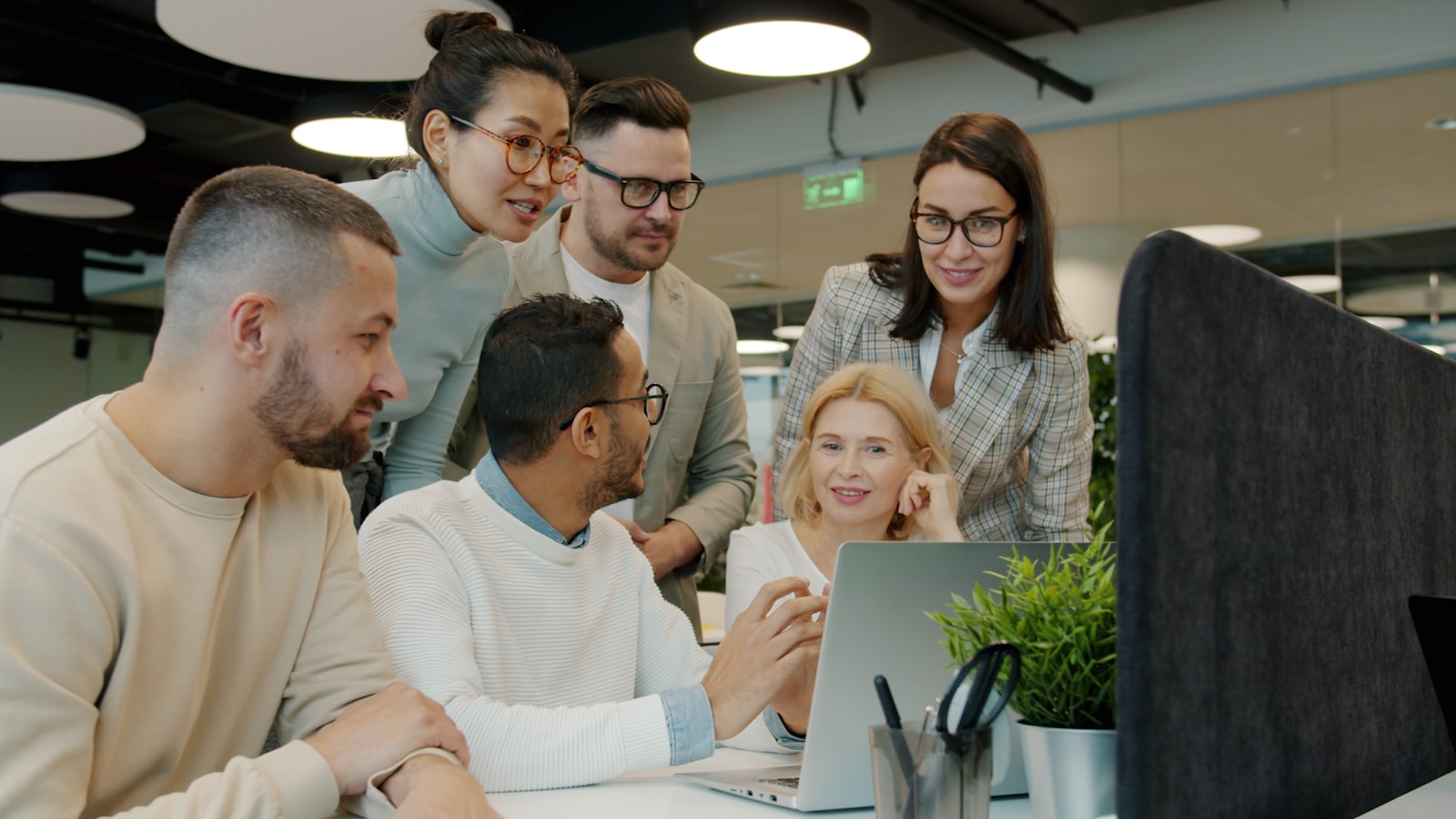 A diverse team clapping and celebrating success while looking at a laptop screen together
