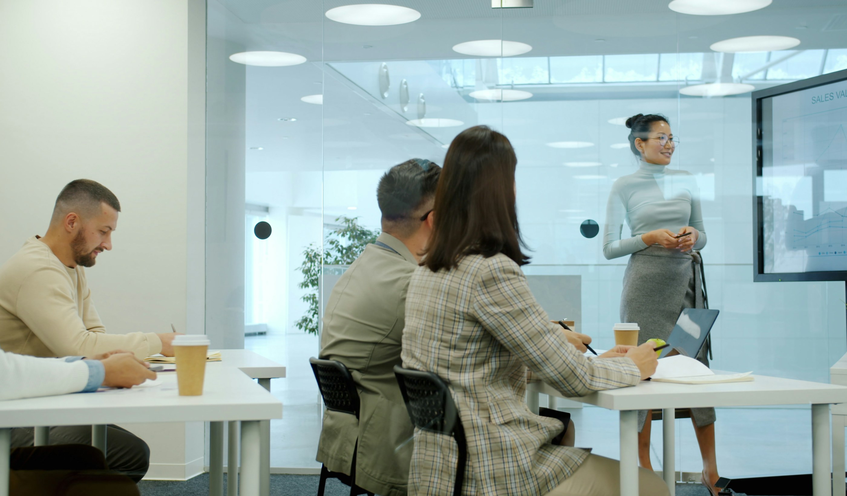 A colleague presenting to several people seated around a table in a modern office