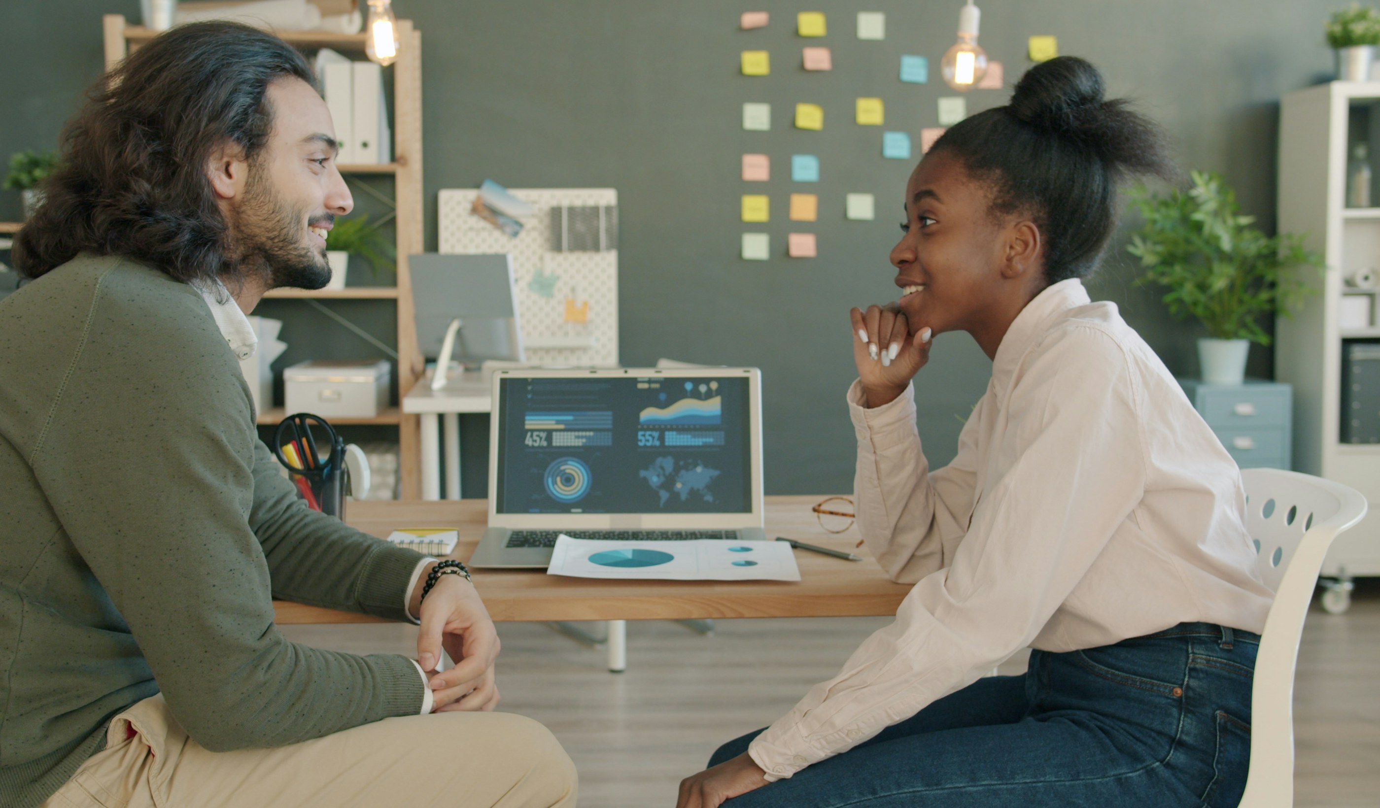 Two colleagues discussing work together at a desk in an office