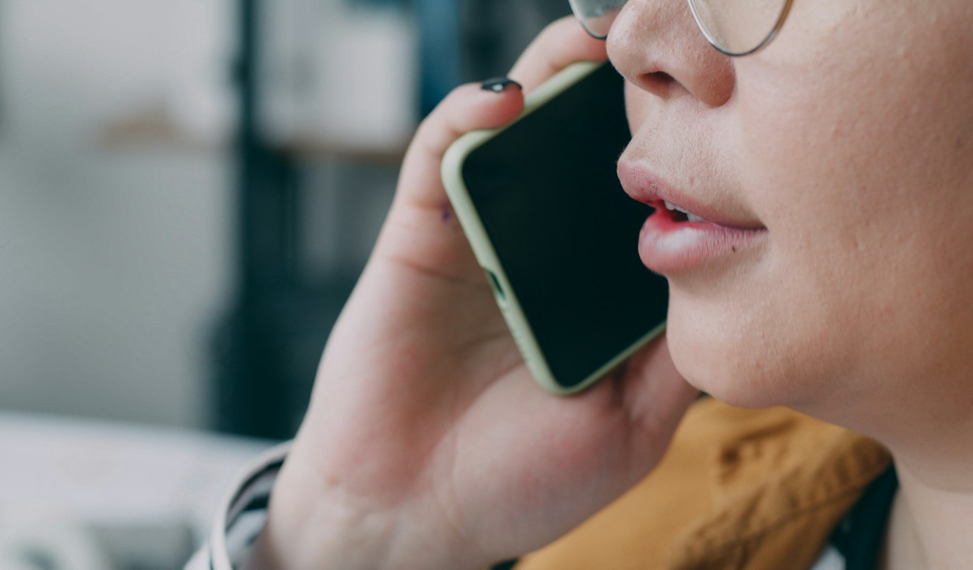 A close-up of a person speaking into a mobile phone held to their face