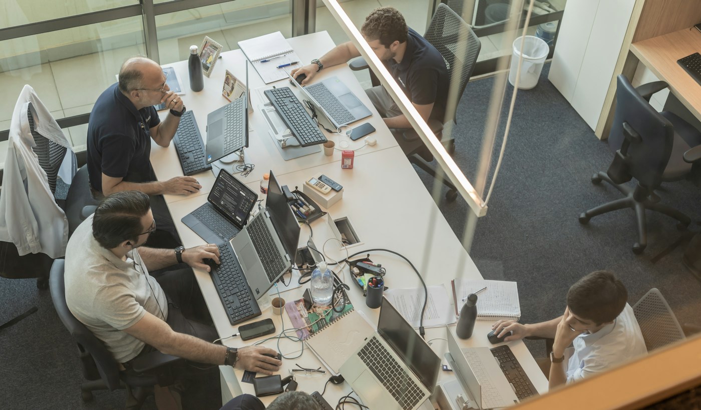 Four colleagues working at desks in an open-plan office seen from above