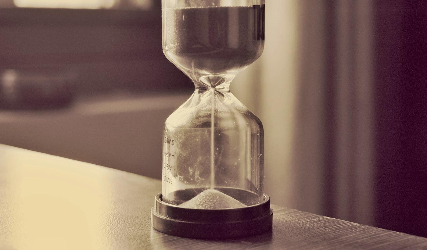 An hourglass on a wooden surface with the sand running through
