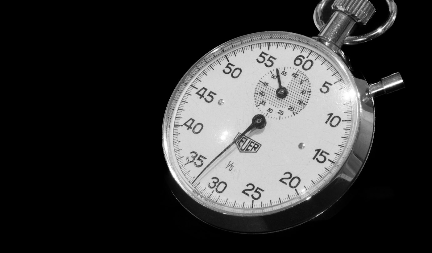 A close-up of a stopwatch on a dark background