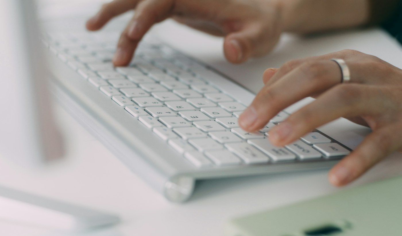 A person typing on a white laptop at a desk