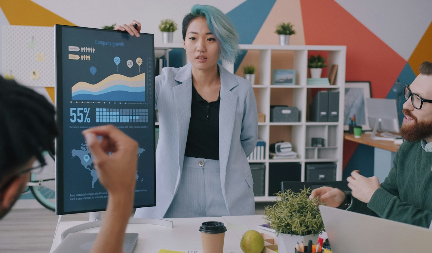 A colleague presenting a chart on a board to two people in an office