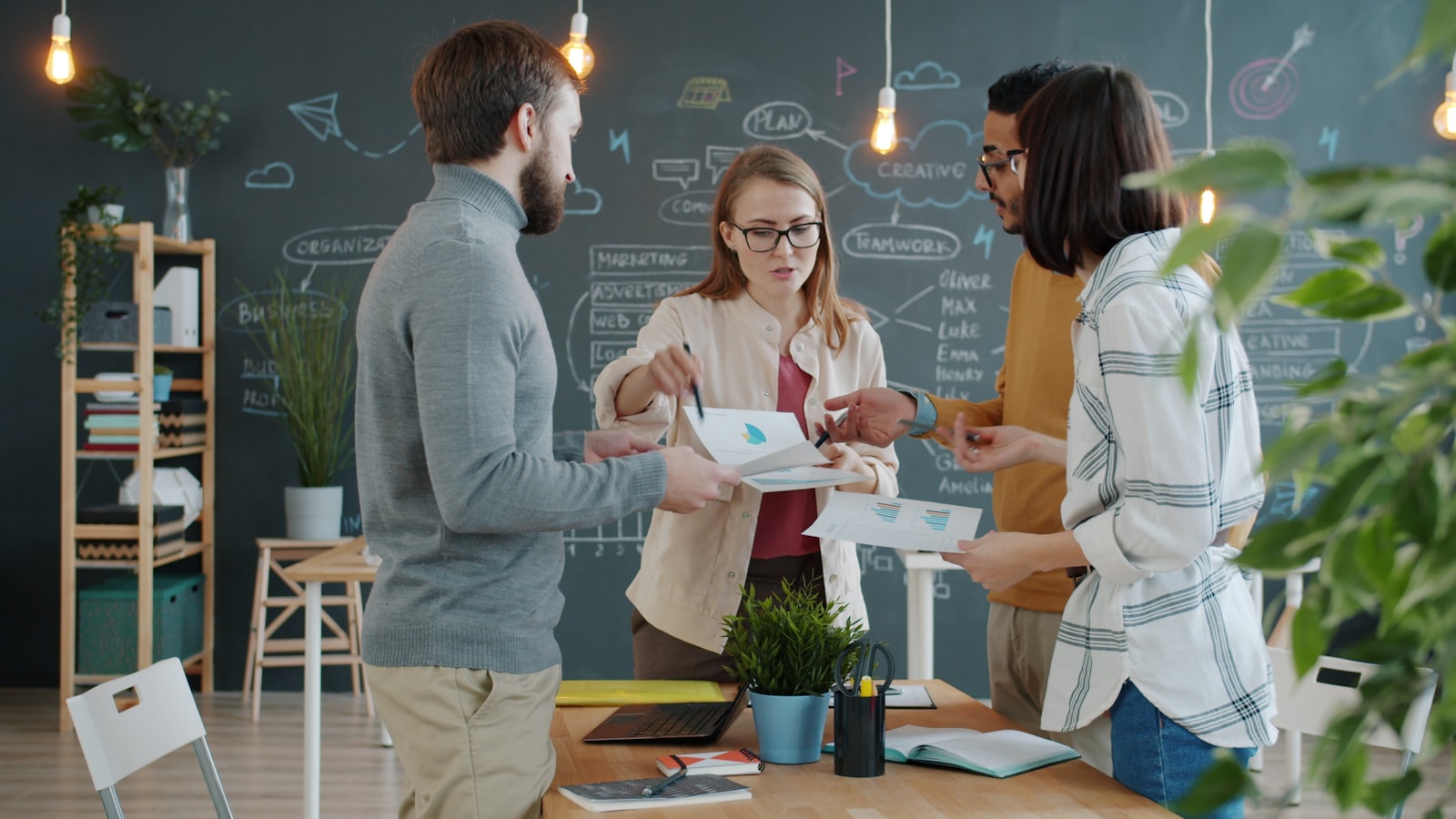 Colleagues gathered around a desk in an office, sharing business ideas over papers